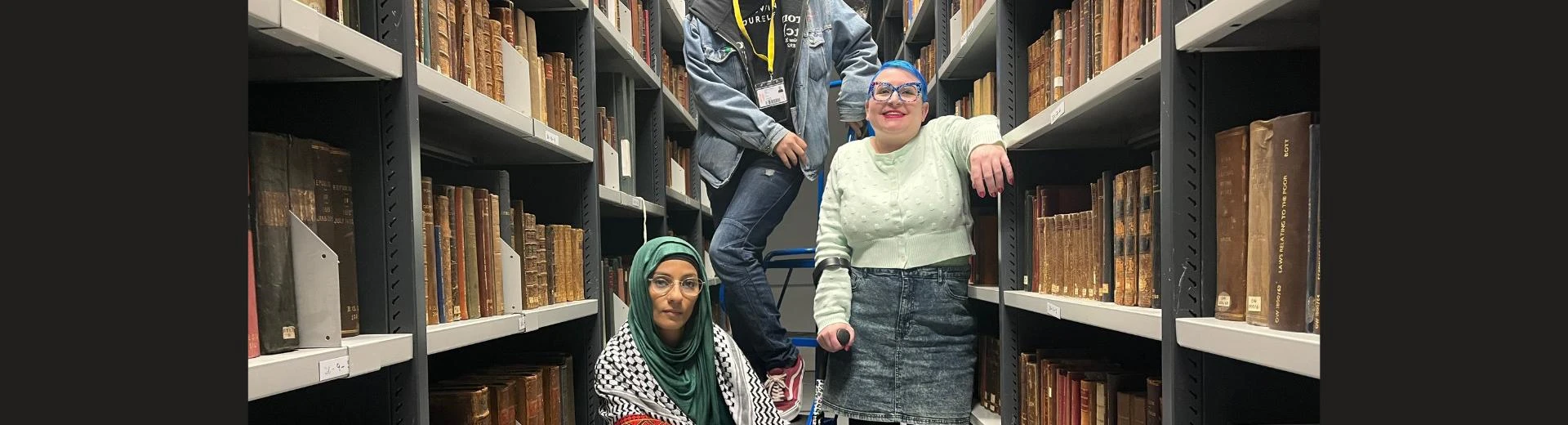 Three people in the archive stacks.