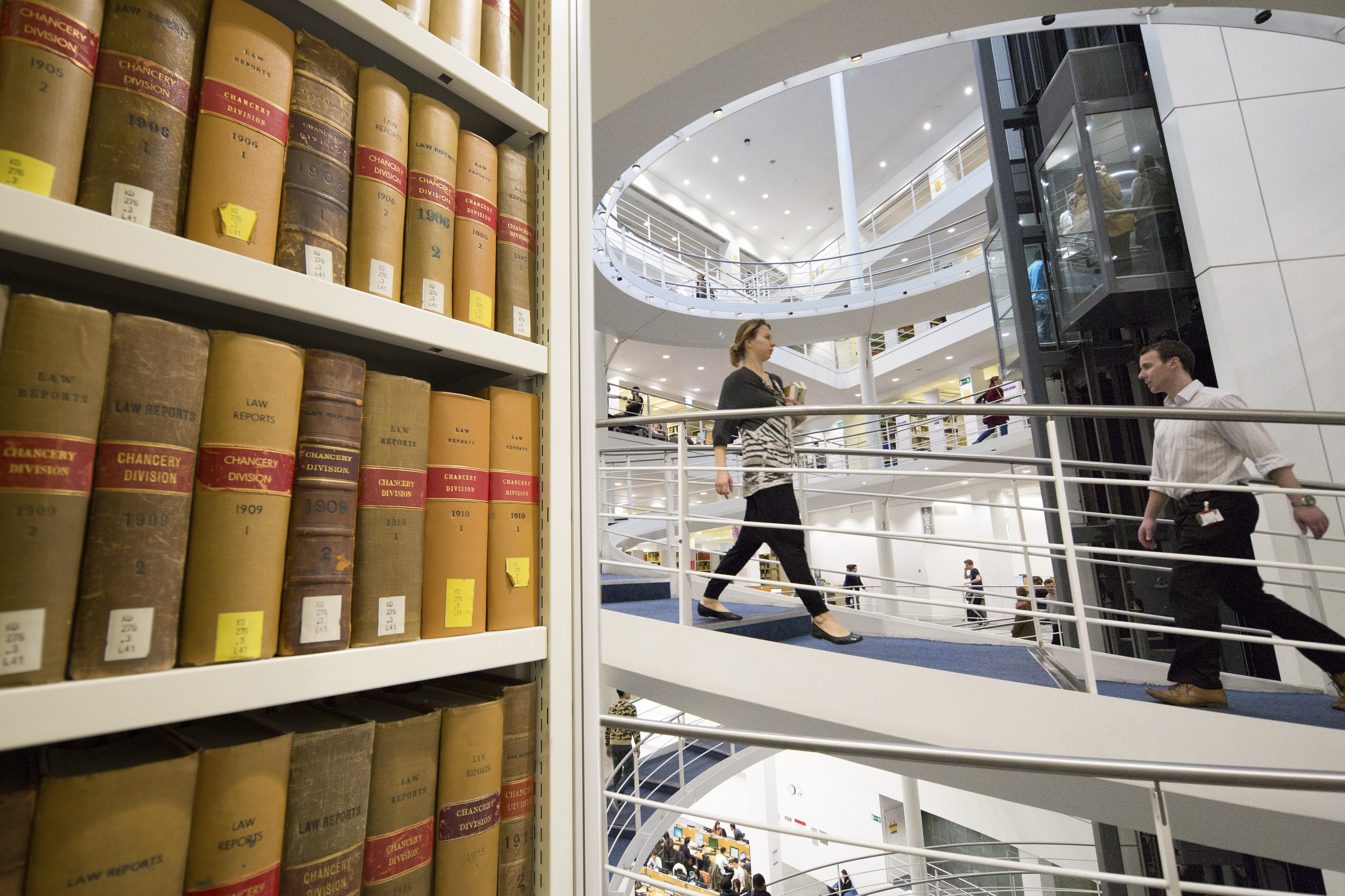 Book stacks and people walking on the Library's spiral staircase.