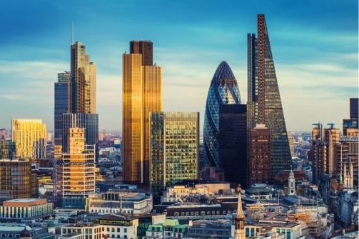 London skyline at sunset featuring glass skyscrapers with golden reflections in the financial district.