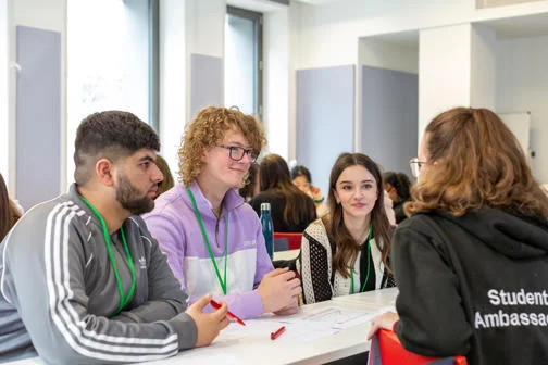 Three WP programme participants talking to a Student Ambassador in a classroom