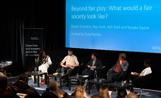 An slide titled "Beyond fair play: what would a fair society look like" with a panel sitting in front.