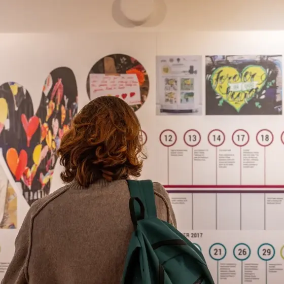 A photo of a woman looking at a Grenfell Tower exhibition