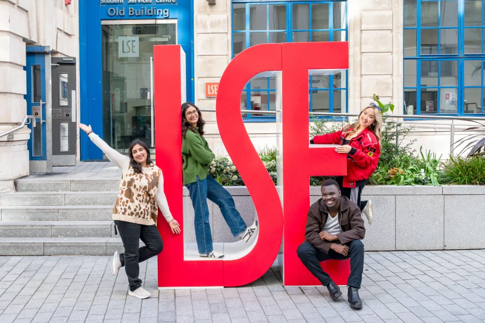Four PBS students by LSE letters on campus