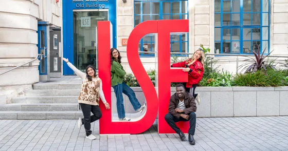 Four PBS students by LSE letters on campus