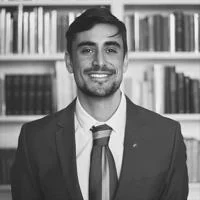 Francisco González Centeno smiling wearing a suit and tie. The photo is black and white.