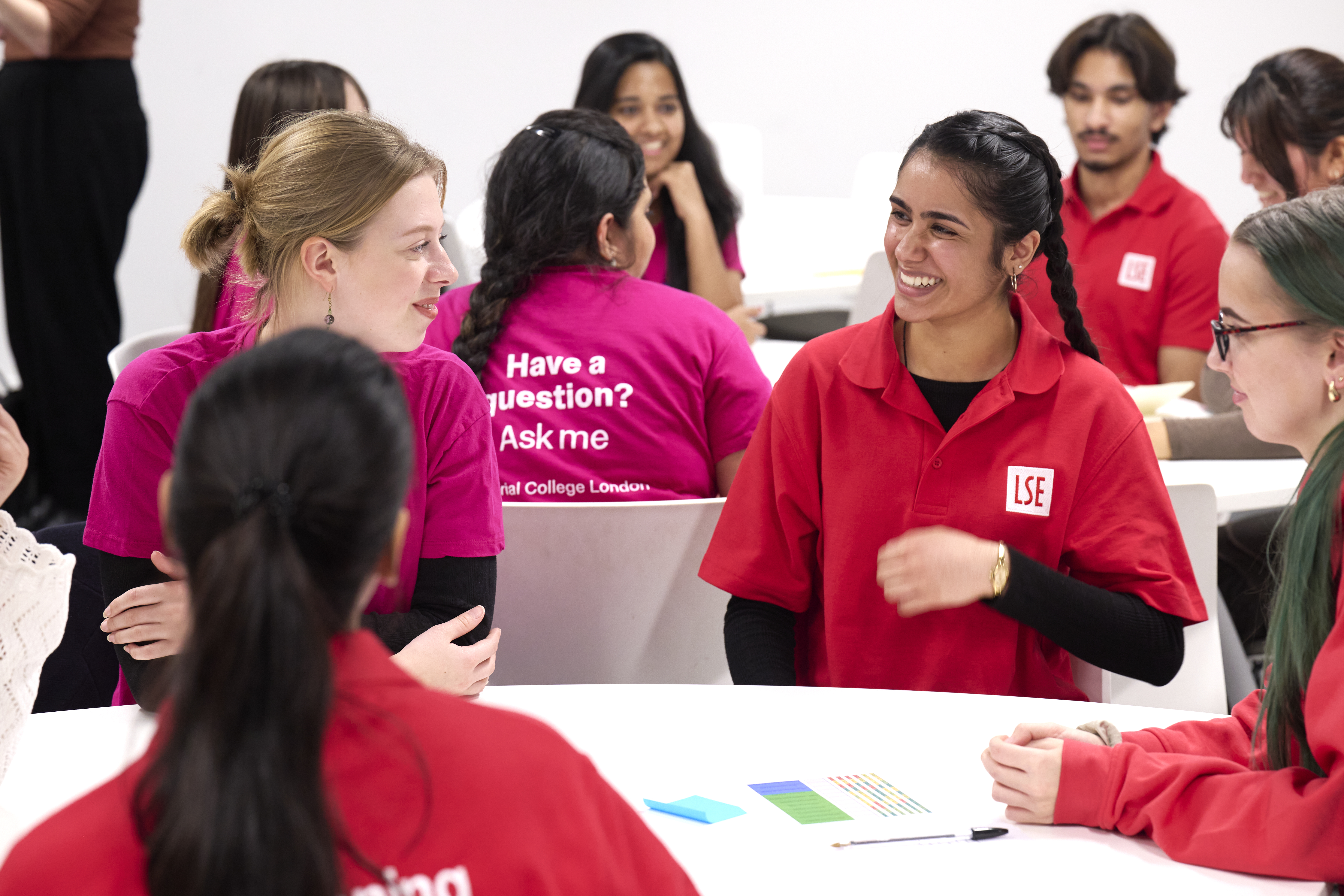 Two mentors in red and pink shirts laugh together.