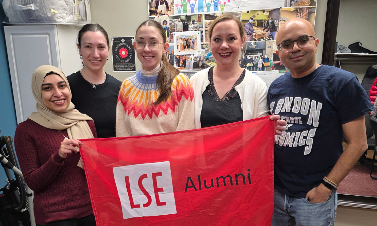 Group of alumni smiling with LSE Alumni flag
