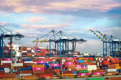A large port with blue cranes and cargo containers