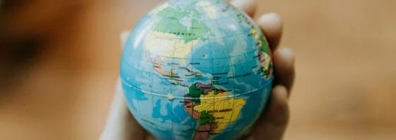 A hand holding a globe