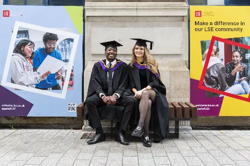 Two graduates sitting on a bench on LSE campus