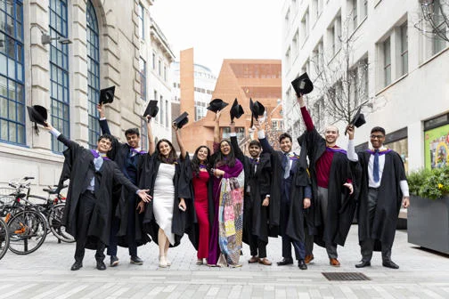 Group of alumni holding up their caps at graduation