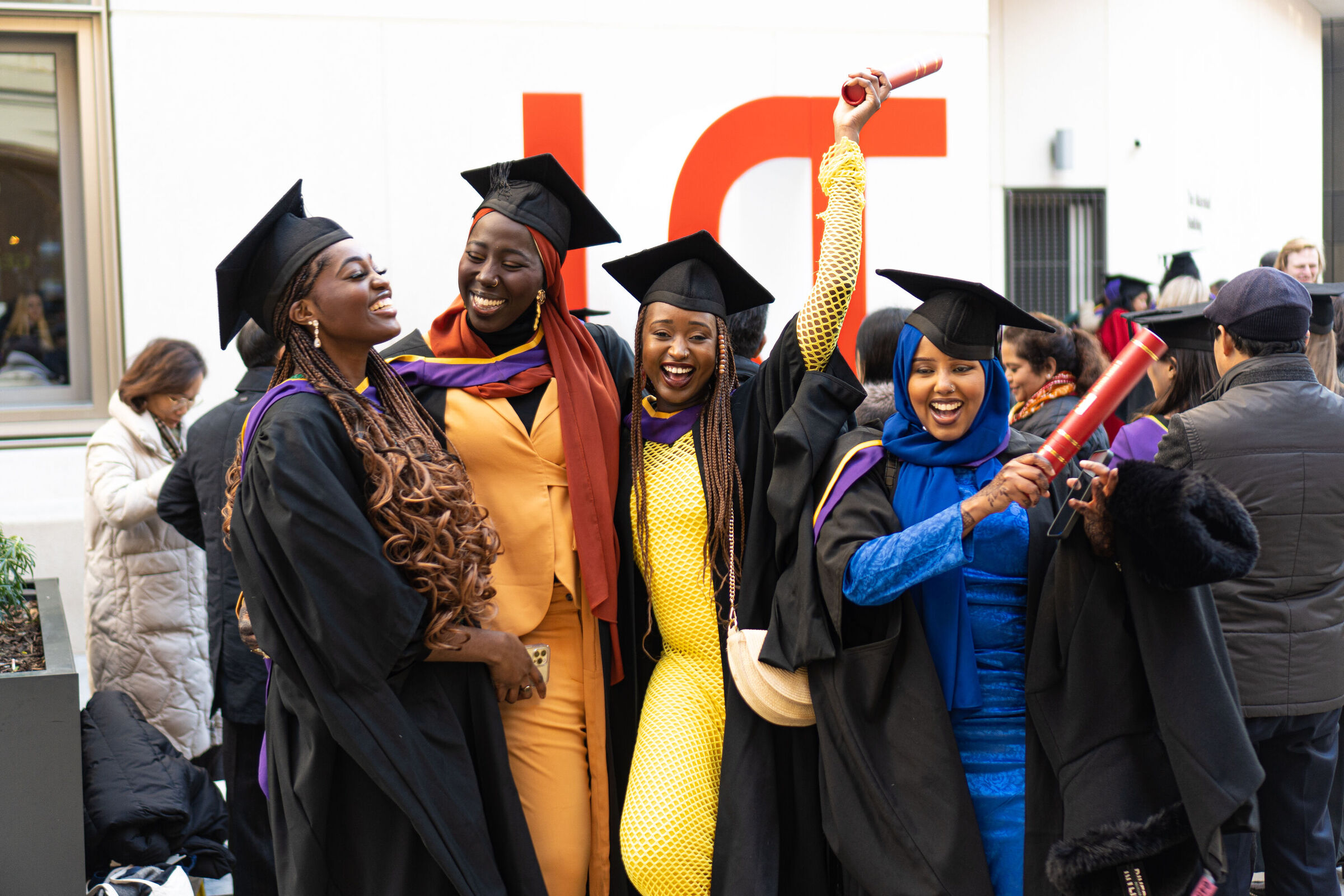 Graduation December 2022. A group of graduates celebrate by the LSE letters.