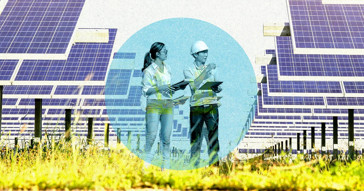 Two people with clipboards stand looking at a row of solar panels