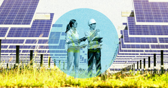 Two people with clipboards stand looking at a row of solar panels