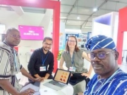 Four researchers at an indoor exhibition booth in a bright event space