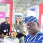 Four researchers at an indoor exhibition booth in a bright event space