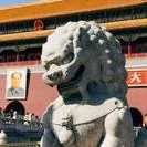 Stone guardian lion statue in front of a historic Chinese palace building with yellow roof and red walls