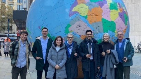 Group of 7 academics standing in front of the large globe sculpture on the LSE campus