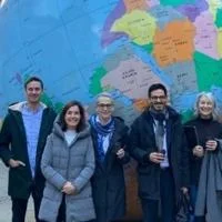 Group of 7 academics standing in front of the large globe sculpture on the LSE campus