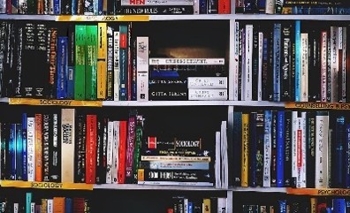 Bookshelf filled with tightly packed books of various sizes and colours, arranged upright and stacked horizontally