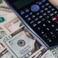 Calculator on a spread of US dollar banknotes of two denominations representing finance, budgeting, and cost analysis