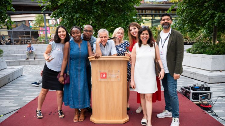 Group of smiling alumni at a podium 