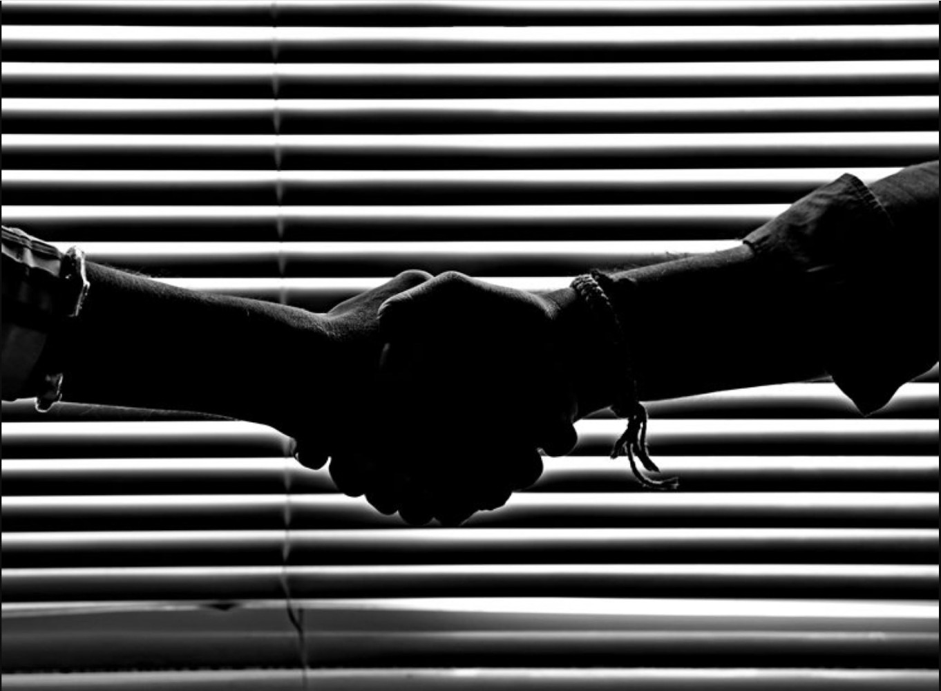 A business handshake in front of window shutters