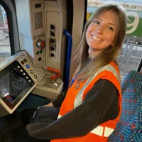 Woman smiles looking at the camera while sitting in a train drivers seat