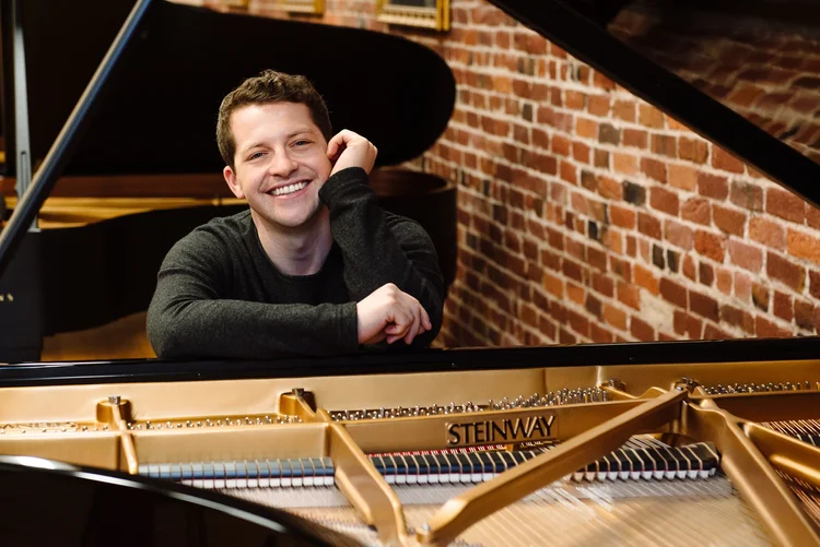 Henry Kramer smiling at piano