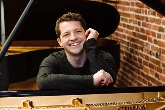 Henry Kramer smiling at piano