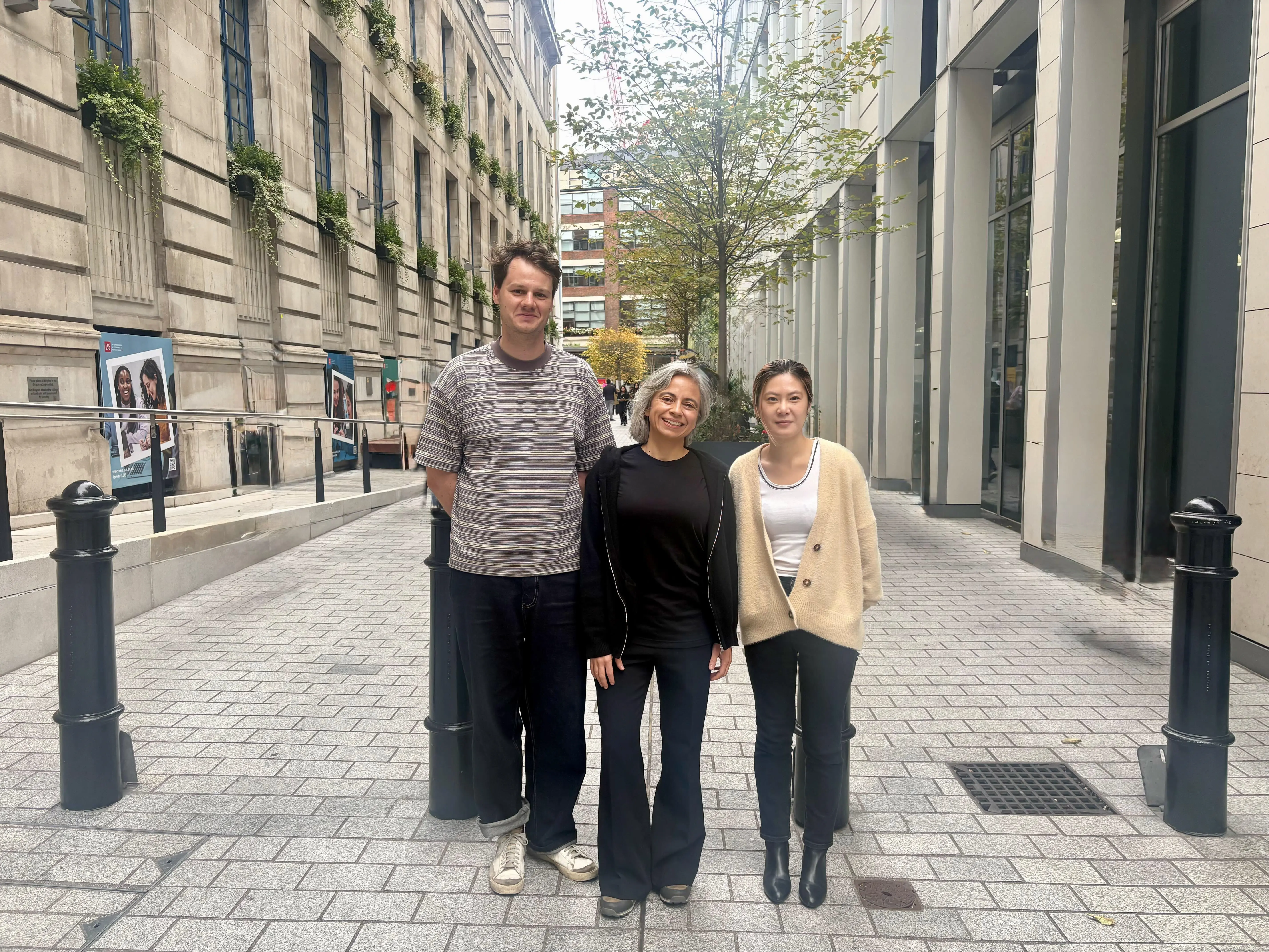 three people stand in the middle of a street, smiling at the camera