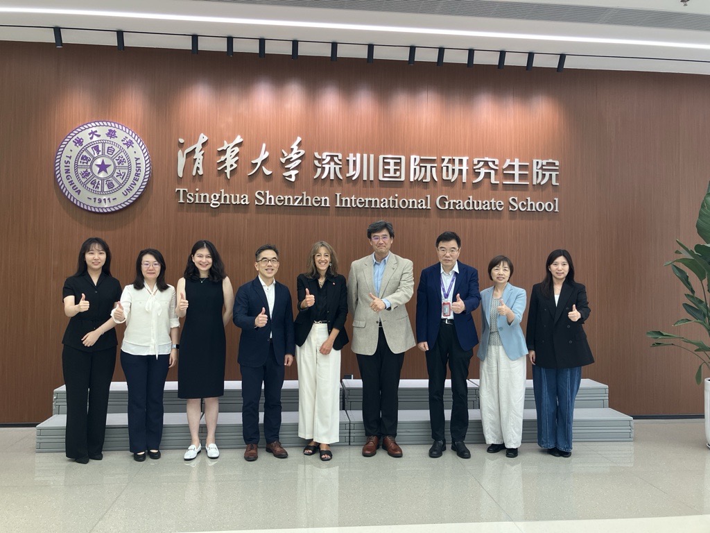 A group of nine individuals posed in front of a wall with the Tsinghua Shenzhen International Graduate School logo. 