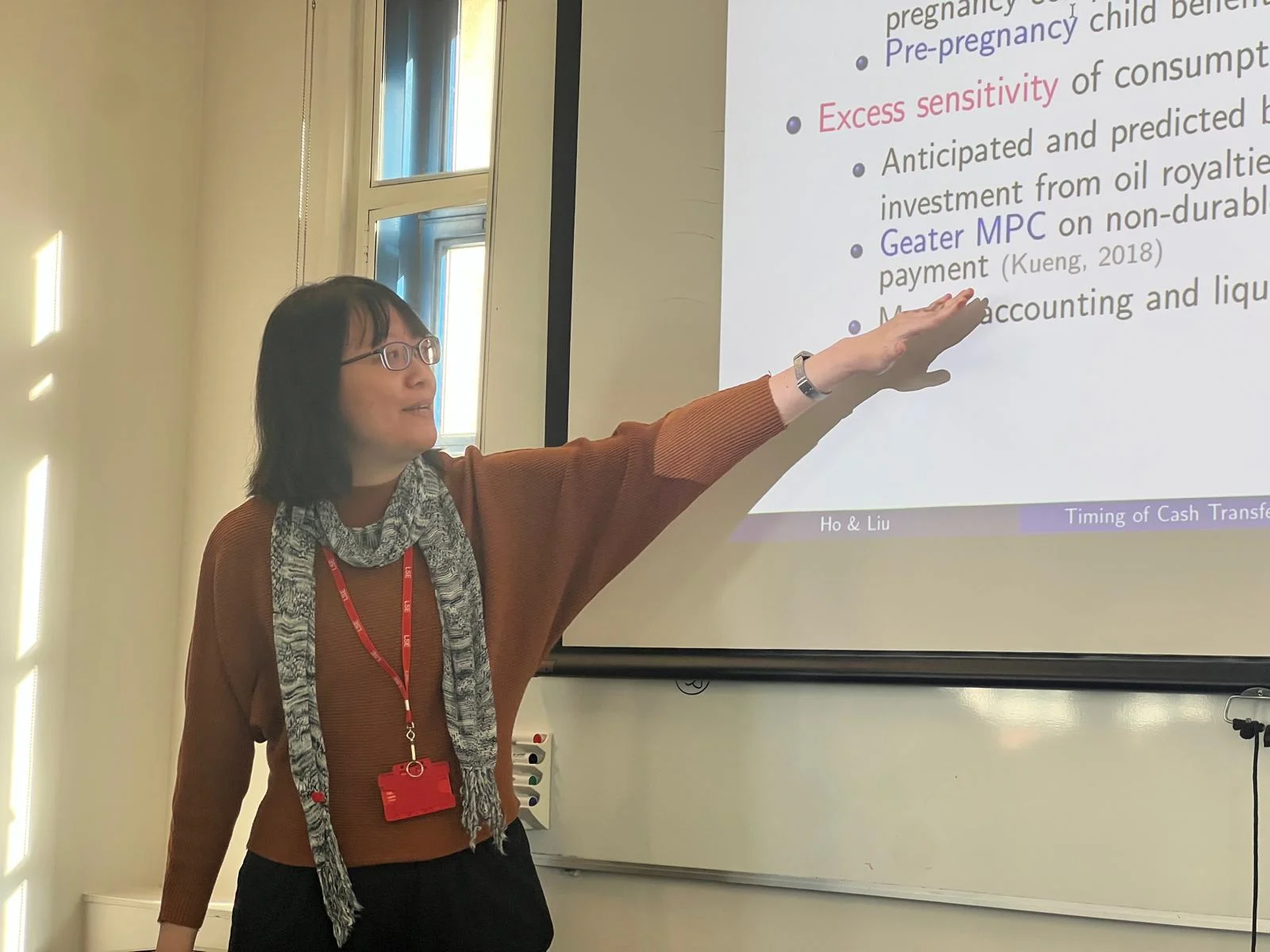 An image of Professor Ho at the front of a classroom speaking at a workshop. She is pointing towards text that is displayed on the screen.