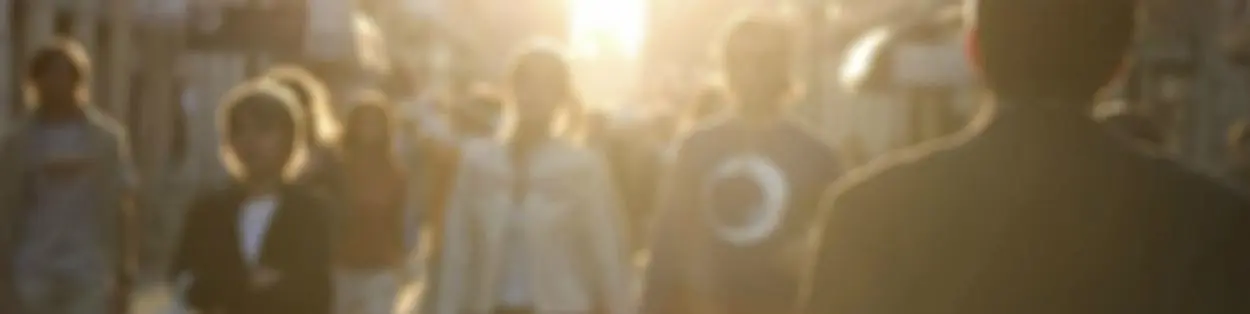 people walking on a busy street with the sun shining down