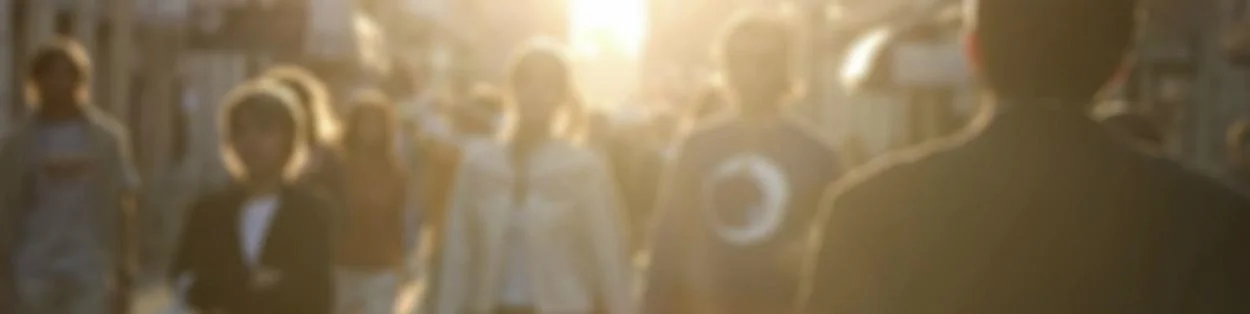 people walking on a busy street with the sun shining down
