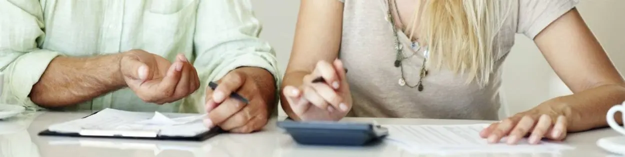 a man and woman using a calculator and writing notes