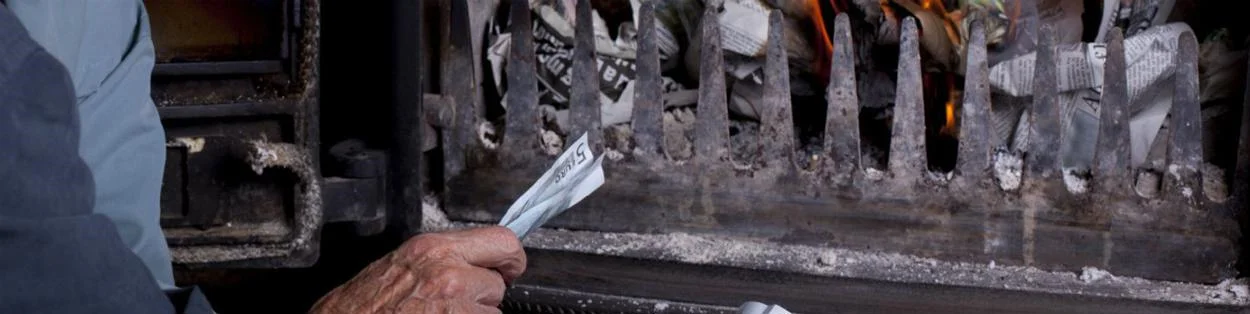 an elderly person holding money to a fire