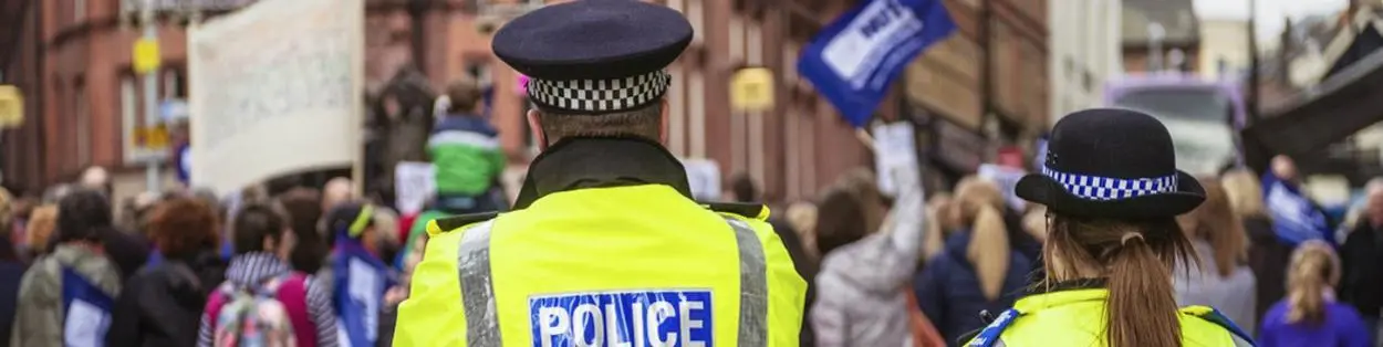 Two police officers standing beside a crowd of protesters.