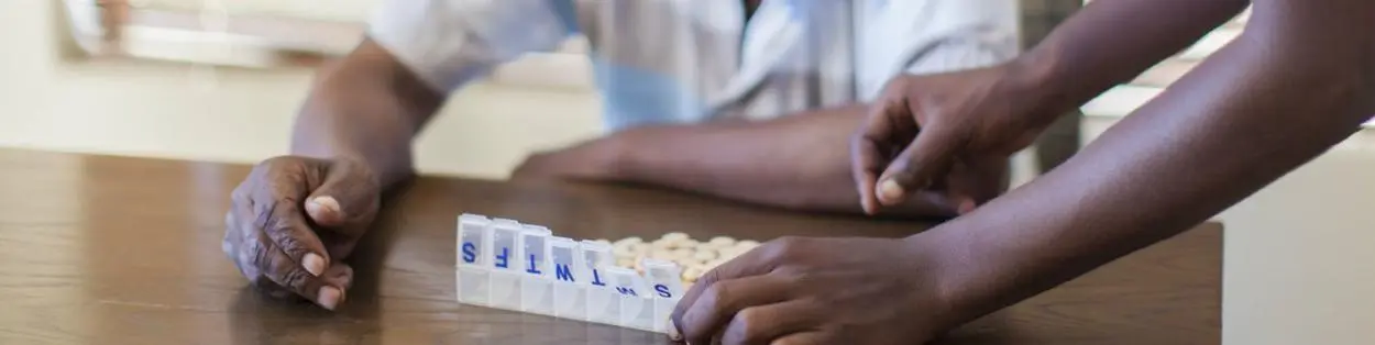 Two men putting pills into a sorting box