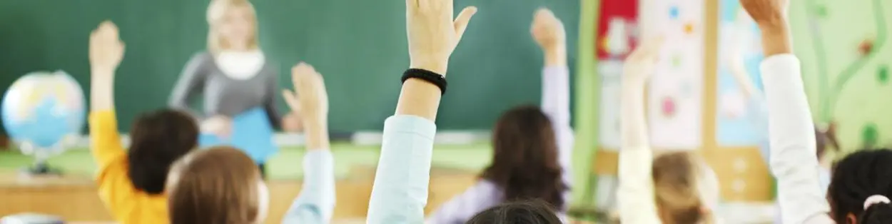 a classroom with children raising their hands