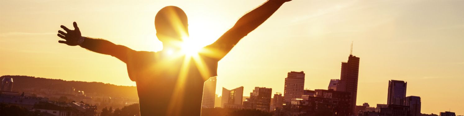 a man with his arms outstretched looking towards a city