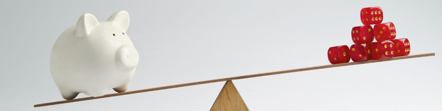 a set of scales with die on one end and a porcelain pig money bank on the other