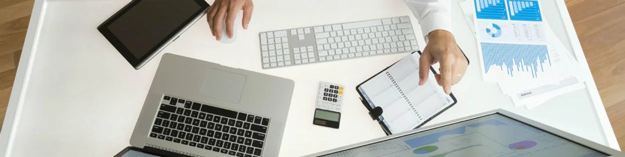 a man working at a desk with a laptop and diary