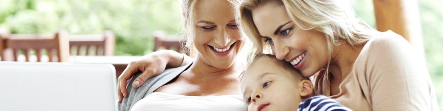 two women and a boy smiling and looking at a computer