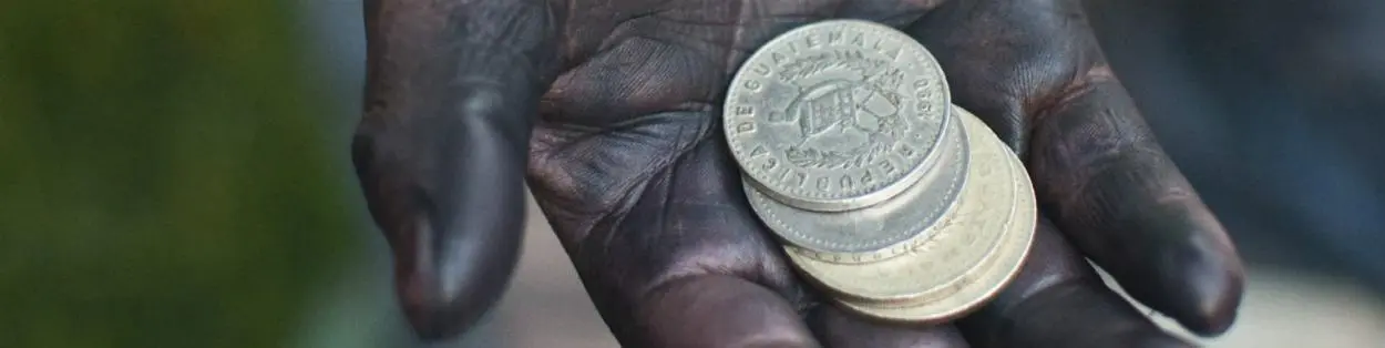 a hand covered in oil holding coins
