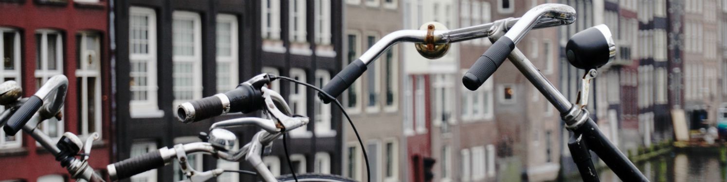 A row of bikes in front of a row of buildings.