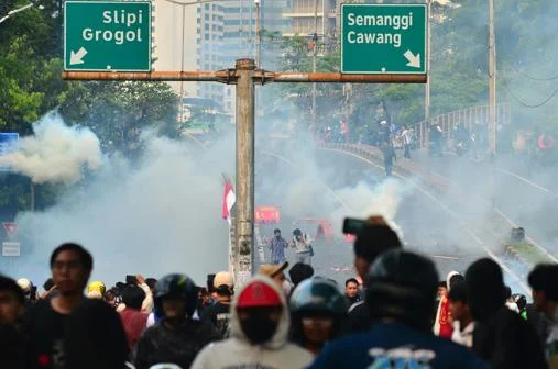 Crowd of protesters shrouded in smoke under highway signs