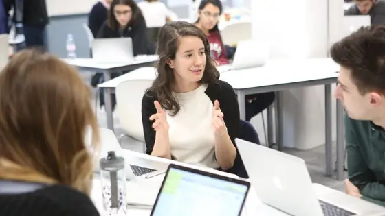 Group of people talking in front of laptops
