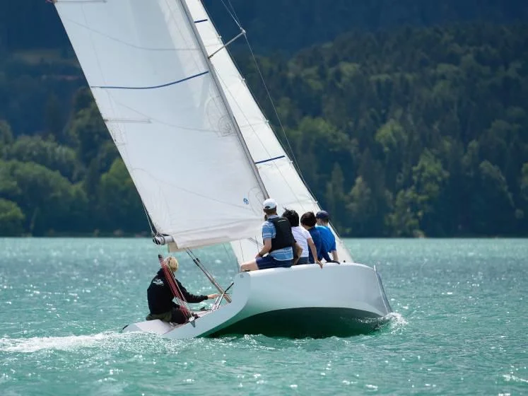 Alumni sail a boat on the blue waters of the Tegernsee