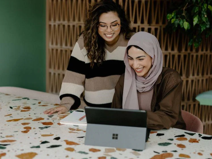 Two women looking at a computer tablet and smiling.